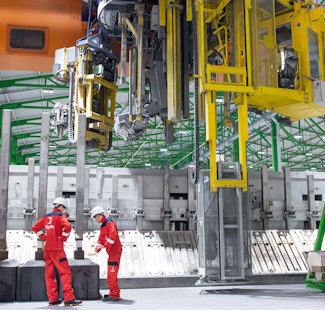 people in red suits standing in front of a large machine people in red suits standing in front of a large machine